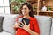 Young latin woman smiling confident hugging bible at home