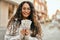 Young latin woman smiling happy holding colombia pesos banknotes at the city