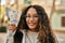 Young latin woman smiling happy holding colombia pesos banknotes at the city