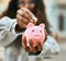 Young latin woman smiling happy saving euro coin in the piggy bank at the city