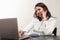 Young latin woman talking by mobile phone and working at home with the laptop. Teleworking concept on a white background