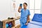Young latin woman wearing physiotherapist uniform make selfie by the smartphone at clinic
