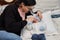 Young latina mother with her newborn baby playing and laughing together on the bed