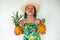 A young Latina in a straw hat holding a whole pineapple fruit, throwing a kiss