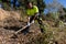 Young Latino male gardener in reflective work clothes digging and clearing land for planting