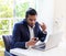 Young latino Man with laptop texting on mobile phone sitting at table