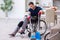 Young leg injured contractor in wheel-chair cleaning the house