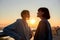 Young lesbian silhouetted couple having romantic moment while listening to music sharing one same earphones, standing on