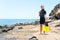 Young lgirl in diving suit with paddles standing on rock coast.