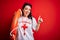 Young lifeguard woman wearing secury guard equipent holding rescue float over red background happy with big smile doing ok sign,