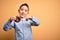 Young little boy kid eating unhealthy chocolate doughnut over isolated yellow background very happy pointing with hand and finger