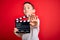 Young little boy kid filming video holding cinema director clapboard over isolated red background with open hand doing stop sign