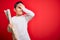 Young little boy kid looking at turist city destination map over red isolated background stressed with hand on head, shocked with