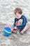 Young little boy playing with the sand and building sandcastle at the beach near the sea.