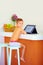 Young little boy watching video through the internet, while sitting in kitchen in the morning