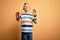 Young little caucasian kid with blue eyes wearing colorful striped shirt over yellow background afraid and terrified with fear