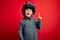 Young little caucasian kid wearing vintage biker motorcycle helmet and googles over red background pointing finger up with