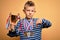 Young little caucasian kid wearing winner medals and victory award trophy over yellow background with angry face, negative sign