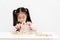 Young little cute asian girl build a house from wooden block construction, wood toy, jenga house on desk in white room studio