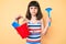 Young little girl with bang playing with summer shovel and bucket toys skeptic and nervous, frowning upset because of problem