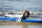 Young little girl on beach taking surfing lessons