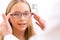 Young little girl trying glasses at the optician