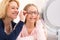 Young little girl trying glasses at the optician w her mother
