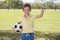 Young little kid 7 or 8 years old enjoying happy playing football soccer at grass city park field posing smiling proud standing ho