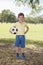 Young little kid 7 or 8 years old enjoying happy playing football soccer at grass city park field posing smiling proud standing ho