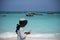 Young local girl on the beach with Turquoise Water and Dhow Boats in Ocean in Nungwi, Zanzibar, Tanzania