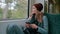 Young lonely Caucasian upset girl in a red cap rides a subway or tram train, uses a smartphone, and looks out the window