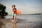 Young long-haired beach lifeguard running in water with lif