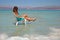 Young long-haired brunette sits on a chair in Israel. The girl in the dead sea looks at the mountains of Jordan