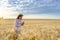 Young long-haired woman agronomist in a straw hat holds stalk of wheat in field