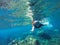 Young loose hair woman snorkeling in blue mask in coral reef
