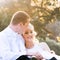 Young in love newly wed couple relaxing in field in golden afternoon sunlight