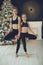 Young lovely woman and girl relaxing next to a Christmas tree and doing a yoga pose. Christmas, holiday, sports.