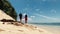 Young lovers holding hands and talking while walking on the white sand beach.