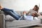 Young loving couple relaxing on sofa together, husband lying on wife legs resting on couch