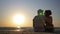 Young loving couple sitting on the beach and kissing