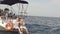 Young loving couple sitting on the feed of sail boat, washing legs in sea water.