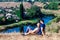 Young loving couple sitting in hug on the top of a hill with wonderful view of the river