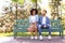 Young loving interracial couple sitting on bench in park on spring day