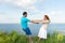 Young loving smiling couple in grass on lake and sky background. Shot of attractive young red hair woman dancing with boyfriend