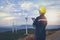 Young maintenance engineer team working in wind turbine farm at sunset on interface data