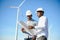 Young maintenance engineer team working in wind turbine farm at sunset stock photo