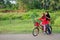 A young malay female children ride a bicycle at their hometown. Smile face from them. View a background of Malay rural village.