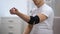 Young male applying elbow padded orthosis, trying to move hand, orthopedics