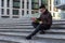 Young male Asian student sitting on steps of University with books