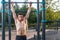 Young male athlete doing chin-up exercises in the park. Fitness man working out outside